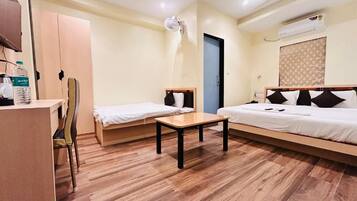 A hotel room with a wooden floor, a desk, two beds, a chair, and a wardrobe.