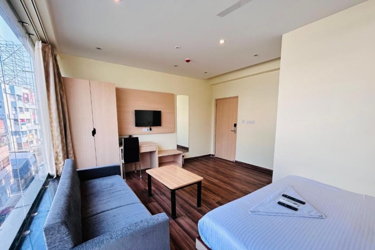A modern hotel room with a sofa, a bed, a desk, and a TV.