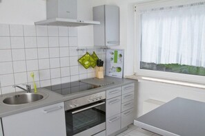 A modern kitchen with a built-in oven, a stainless steel sink, and a window with a view of greenery. - "Bernkastel Moselle Panorama" (Bernkasel-Kues)