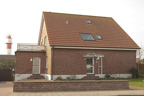 Ein zweistöckiges Backsteinhaus mit Satteldach, einer kleinen Veranda und einem sichtbaren Schornstein.