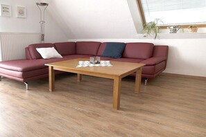A modern living room with a wooden coffee table, a red leather sofa, and a floor lamp. - House Bekaan on the south beach - attic (Borkum)