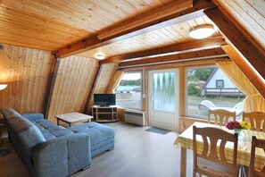A cozy room with a sofa, a small table, and a television. - Holiday island Tietzowsee - Finnish house (Zechlinerhütte)