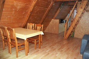 A wooden dining table with chairs, a checkered tablecloth, and a kitchen area with cabinets and a countertop. - Holiday island Tietzowsee - Finnish house (Zechlinerhütte)