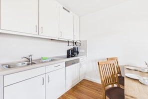 A modern kitchen with white cabinets, a stainless steel sink, and a coffee maker. - Holiday apartment Uhlenkamp 4 (Langeoog)