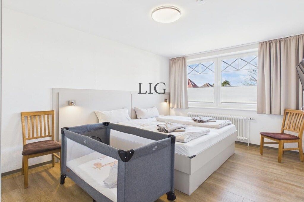 Ein Schlafzimmer mit einem Etagenbett, einem kleinen Doppelbett, zwei Stühlen, einem Fenster mit Vorhängen und einer Heizung.