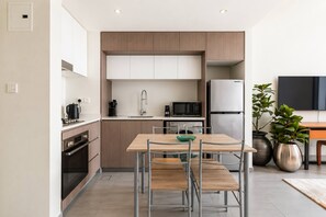 Een moderne keuken met een eethoek, roestvrijstalen apparatuur en een minimalistisch design.