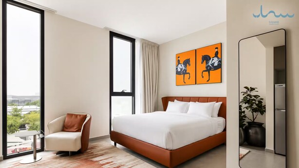Habitación de hotel con una cama grande, una silla, un ventanal y un cuadro en la pared.