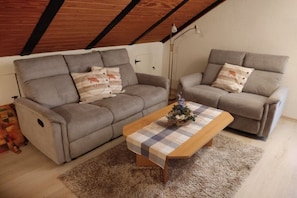 A living room with two grey sofas, a wooden coffee table, and a patterned rug. - Holiday apartment with 1 bedroom (Wunstorf\/ Steinhude)
