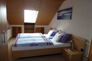 Ein Schlafzimmer mit einem großen Bett, einem Nachttisch, einem Schreibtisch und einem Oberlicht.