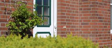 A white door with green trim, set in a brick wall.