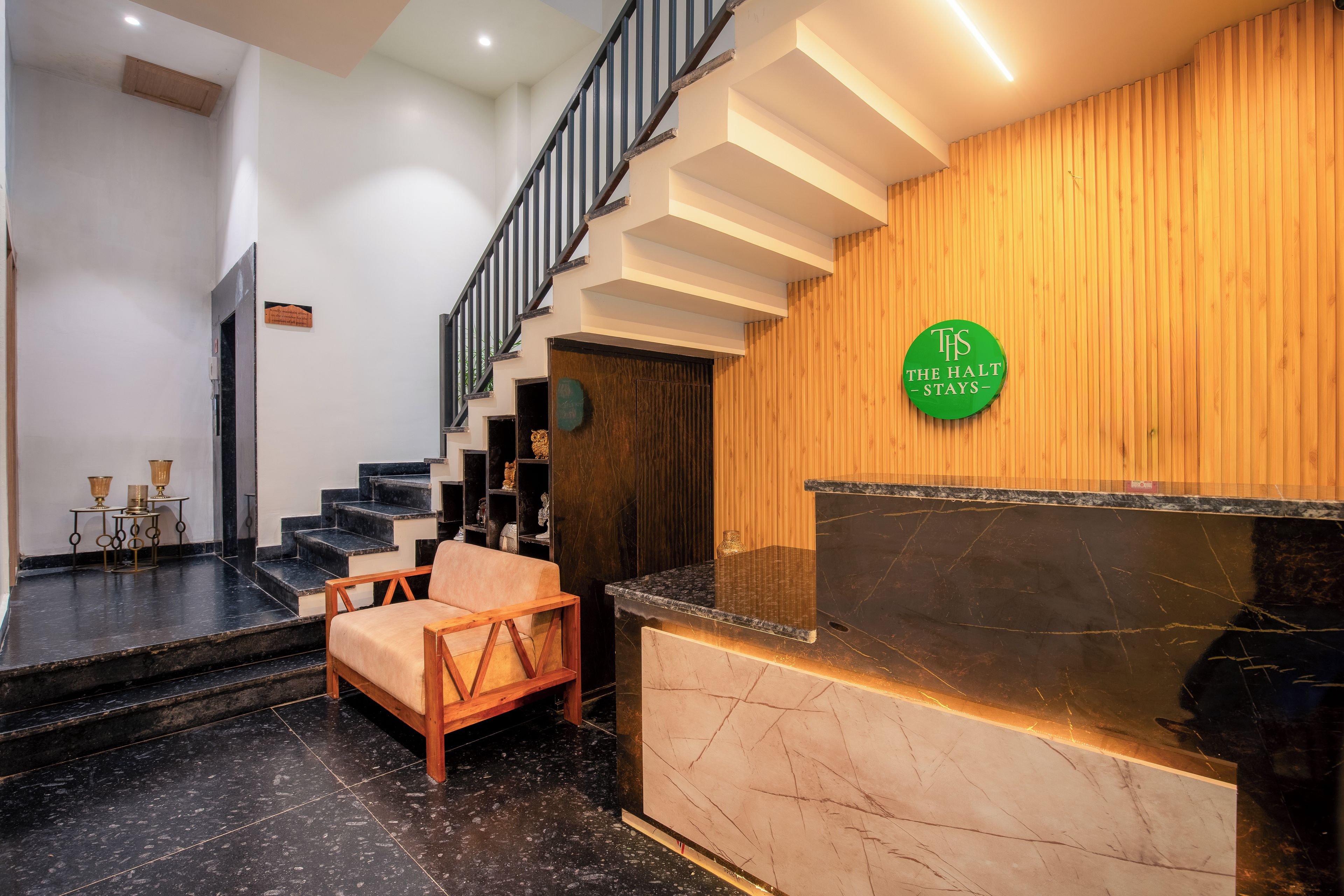Zona de recepción de hotel con pared de madera, mostrador de recepción y una escalera.