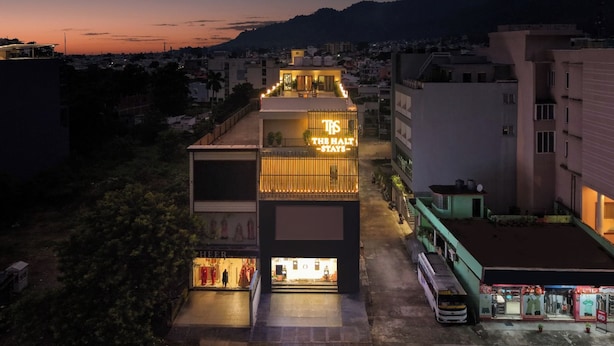 Un hotel con un letrero llamativo, una tienda en la planta baja y un área de estacionamiento.