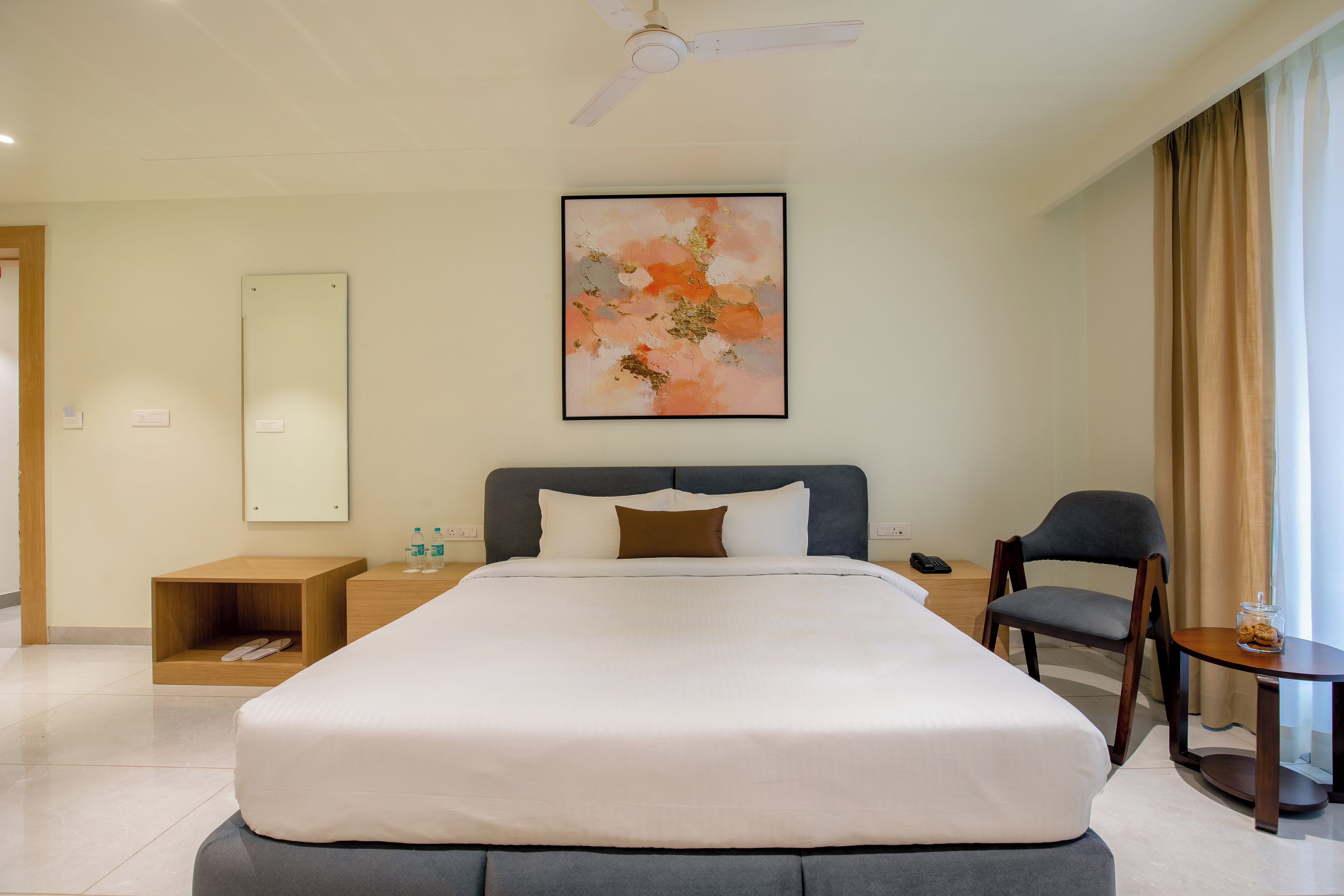 Ein Hotelzimmer mit Bett, Sessel, Nachttisch, Telefon und einem Bild an der Wand.