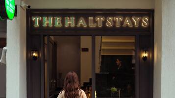 A hotel entrance with a neon sign reading 'THE HALTSTAYS' and a visible entrance door.