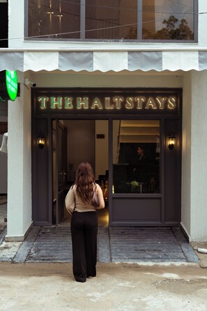 A hotel entrance with a neon sign reading 'THE HALTSTAYS' and a visible entrance door. - The Halt Stays (Haldwani)