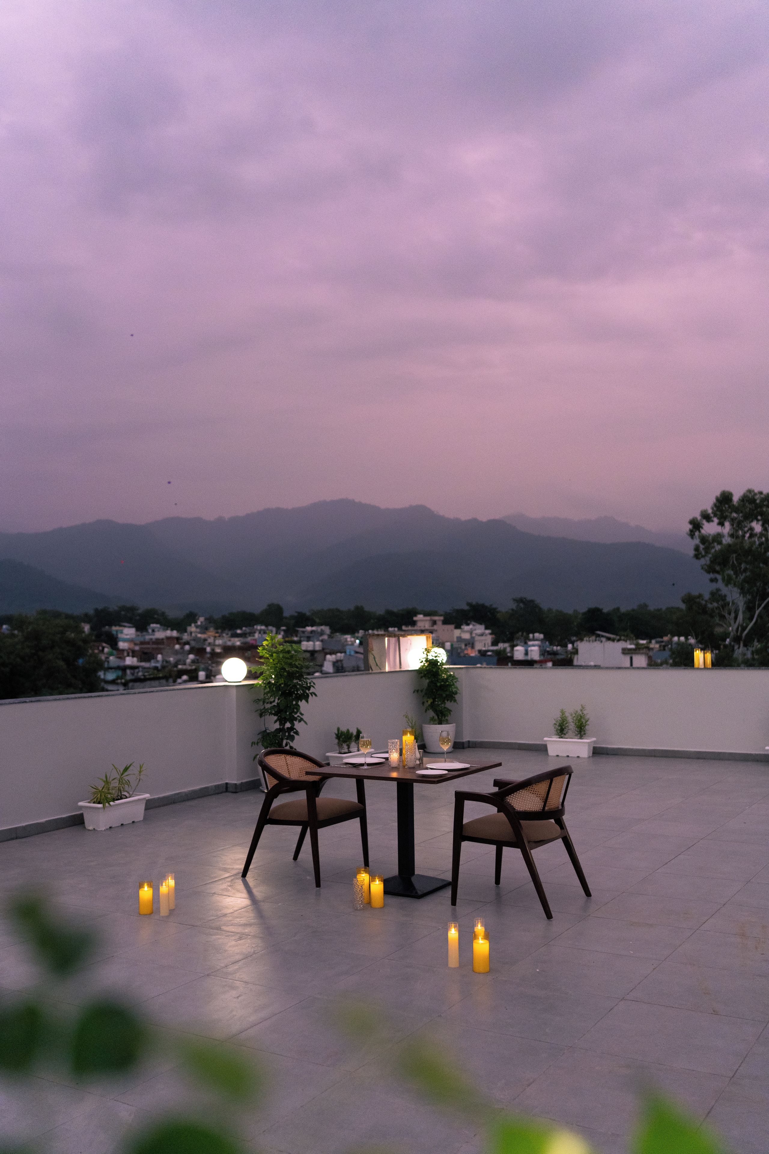 Una terraza en la azotea con mesa y sillas, velas y vistas a montañas lejanas.