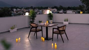 Una terraza en la azotea con mesa y sillas, velas y vistas a montañas lejanas.