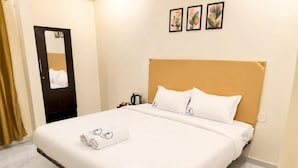 Una habitación de hotel con una cama, una mesita de noche, un espejo y una puerta.