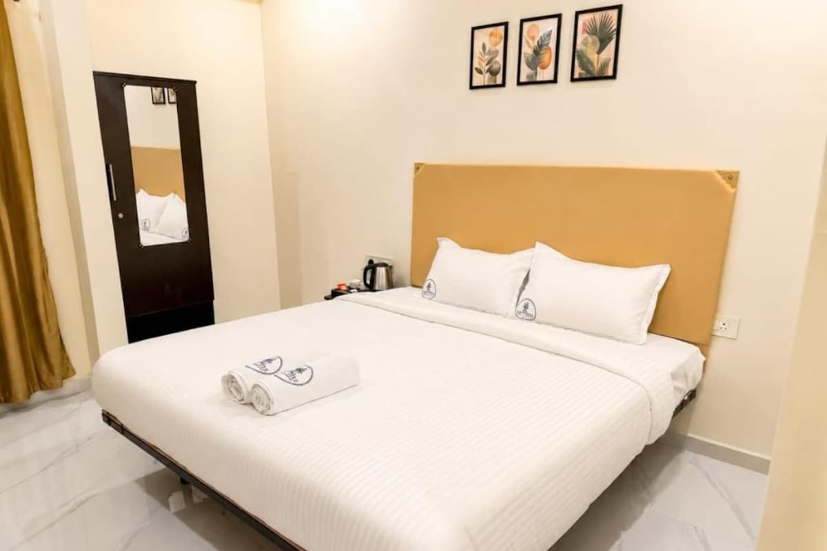 Una habitación de hotel con una cama, una mesita de noche, un espejo y una puerta.