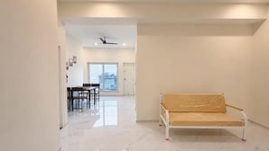 Un pasillo espacioso con un sofá blanco, un comedor y un ventilador de techo.