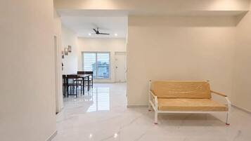 A spacious hallway with a white sofa, a dining area, and a ceiling fan.