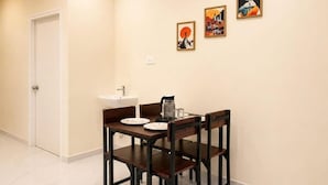 Un comedor con una mesa, sillas, un lavamanos y tres cuadros enmarcados en la pared.