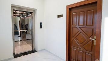 A hallway with a wooden door labeled 'C-Flat' and a glass elevator entrance.