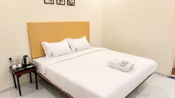 Una habitación de hotel con cama, mesita de noche, cafetera y toalla.