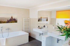Un baño moderno con bañera, dos lavamanos y un espejo.