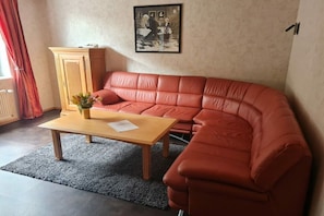 A living room with a red leather sofa, a wooden coffee table, and a cabinet. - at the Eifel National Park (Nideggen)