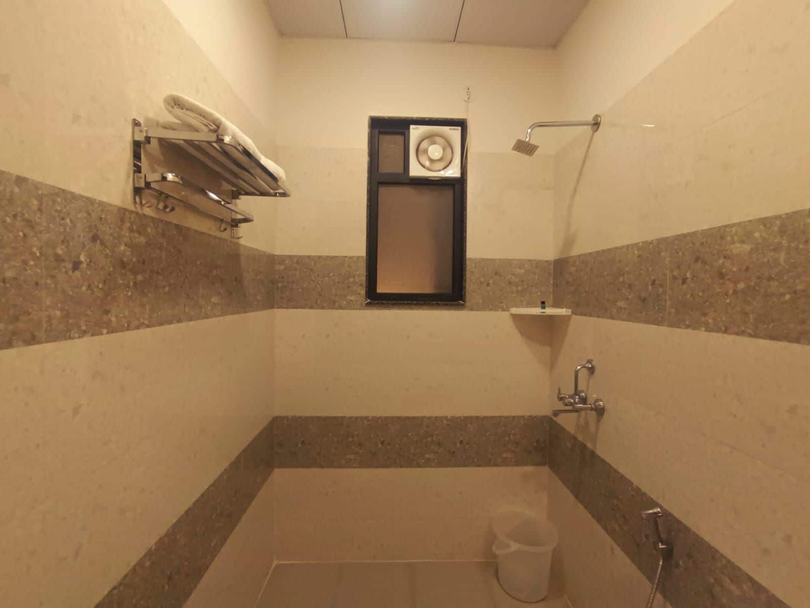 Un baño pequeño con azulejos, una ducha, un perchero y una ventana.