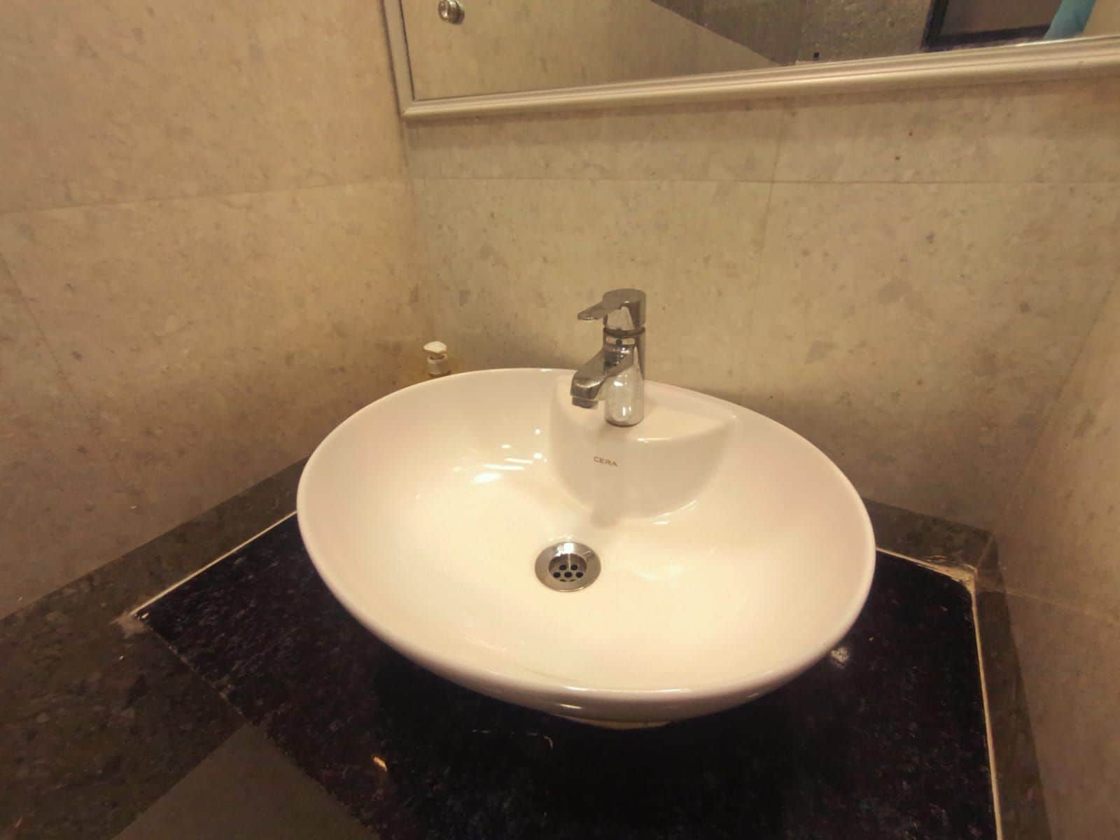 Un baño con un lavabo blanco, un solo grifo y un espejo encima.