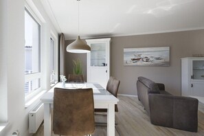 A modern living room with a dining area, a sofa, and a painting on the wall. - Holiday apartment with 1 bedroom (Cuxhaven)