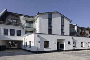 Een modern gebouw met een plat dak, meerdere balkons en een hekwerk.