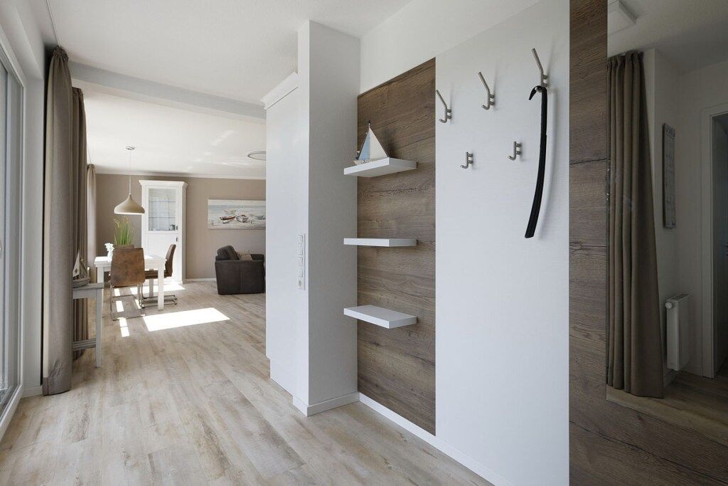 Ein modernes Interieur mit Holzboden, weißen Wänden und einem Essbereich mit Tisch und Stühlen.