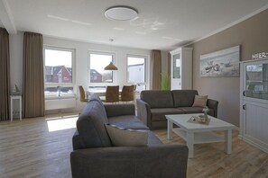 Un salon moderne comprenant un canapé, une table basse et un coin repas avec des chaises.