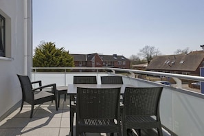 A balcony with a table and chairs, overlooking a residential area with houses and a tree. - Holiday apartment with 1 bedroom (Cuxhaven)