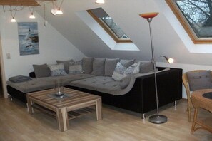 Een moderne woonkamer met een modulaire bank, een bijzettafeltje, een vloerlamp en een schilderij aan de muur.