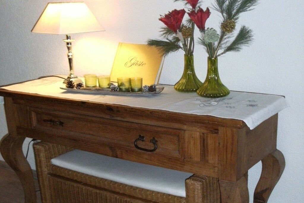 Et natbord i træ med en lampe, et kort og to vaser med blomster.