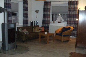 Ein Wohnzimmer mit Kamin, einer Couch, einem Sessel und einem Tisch.