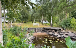 Eine natürliche Landschaft mit Teich, Holzbrücke und Bank.