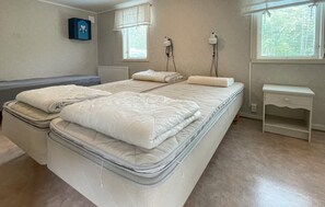 Ein Schlafzimmer mit einem Bett, Nachttischen und einem Fenster mit Jalousien.