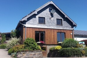 A two-story house with a sloped roof, wooden siding, and a satellite dish. - Holiday apartment in Monschau with barbecue (Monschau)