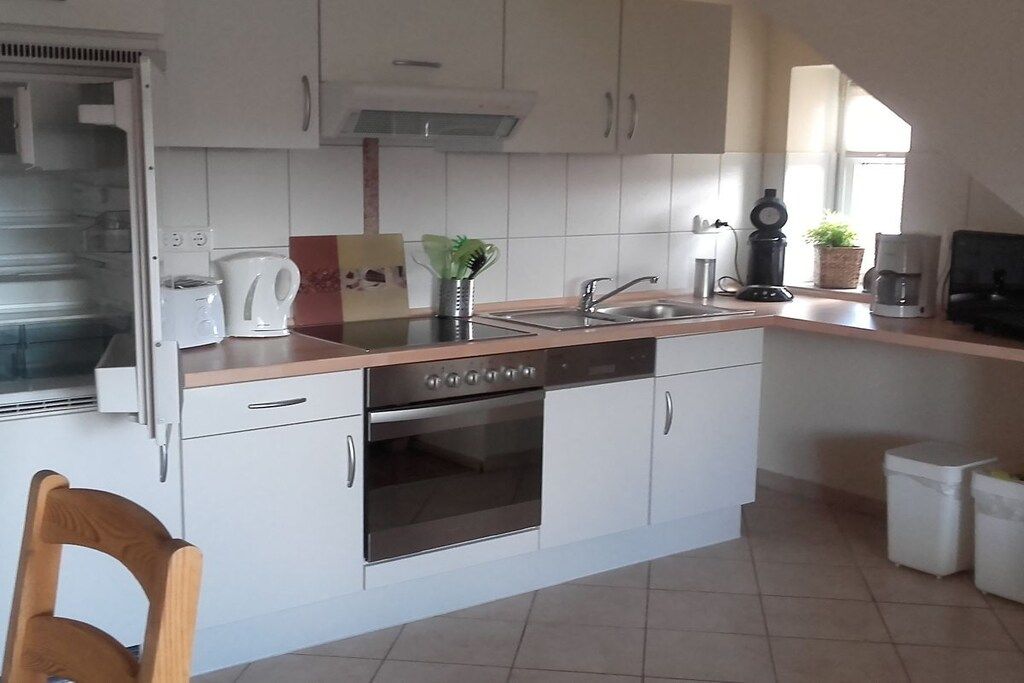 A compact kitchen with white cabinets, a built-in oven, a coffee maker, and a sink.