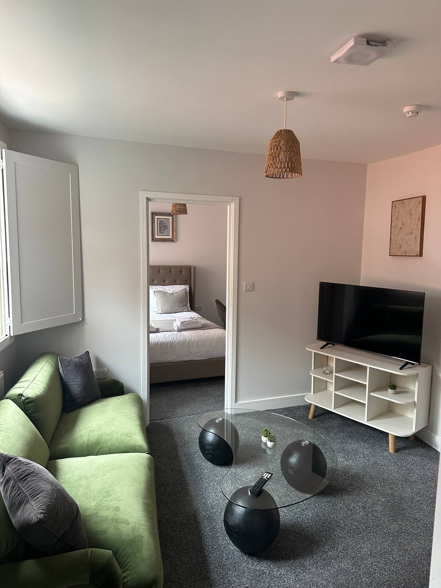 Una sala de estar moderna con un sofá verde, un televisor de pantalla plana y un diseño minimalista.