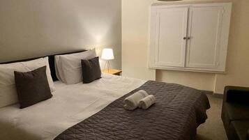 Una habitación de hotel con una cama, una mesita de noche, una lámpara y un armario.