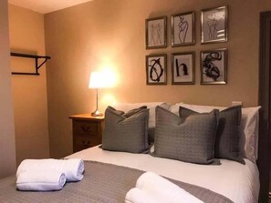 Una habitación de hotel con una cama, una mesita de noche, una lámpara y decoración en la pared.