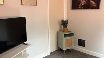 A living room with a flat-screen TV, a green cabinet with a plant, and a large painting of a bull.