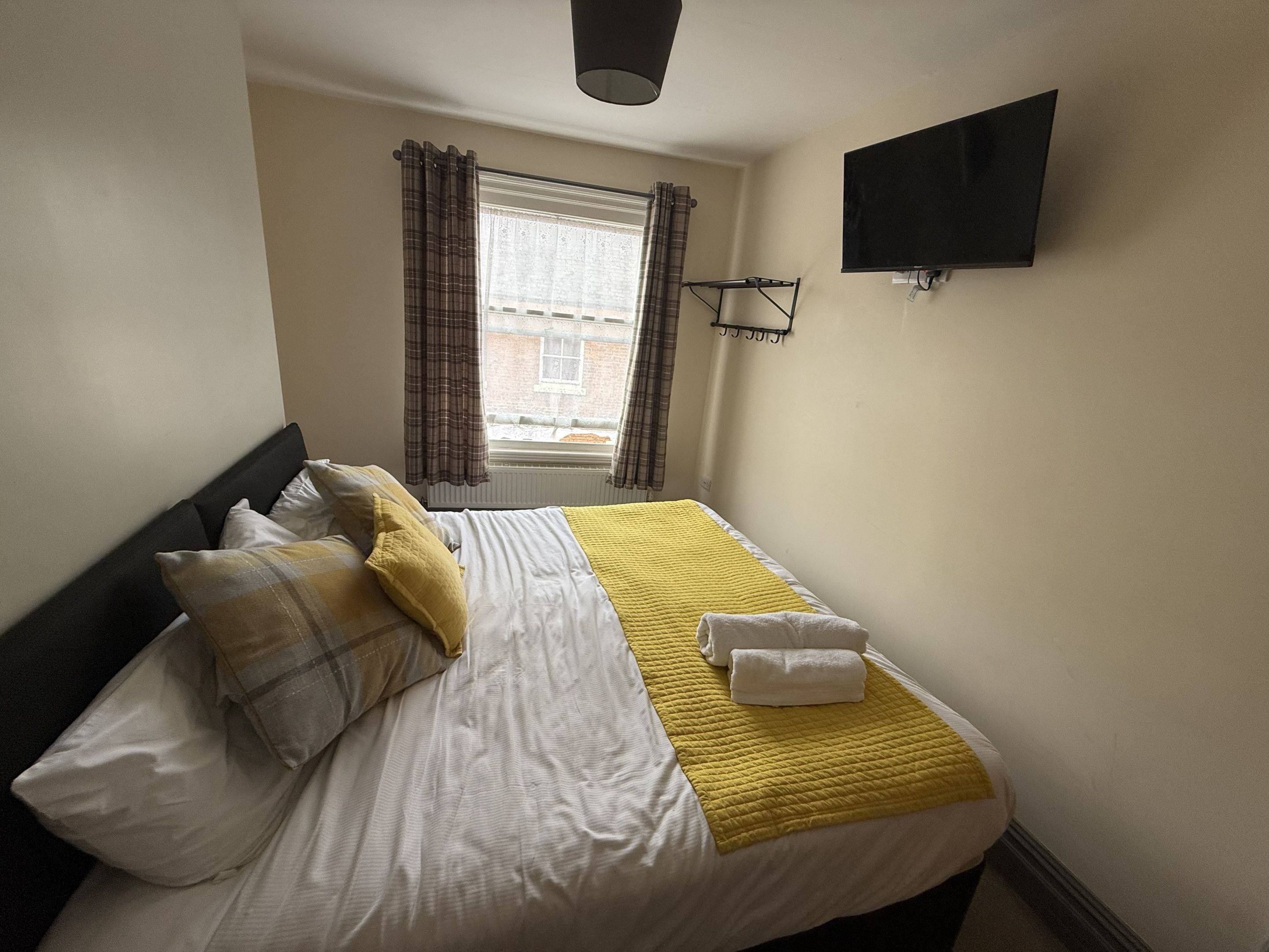 Ein Hotelzimmer mit einem Bett, einem flachbildfernseher an der Wand und einem Fenster mit Vorhängen.
