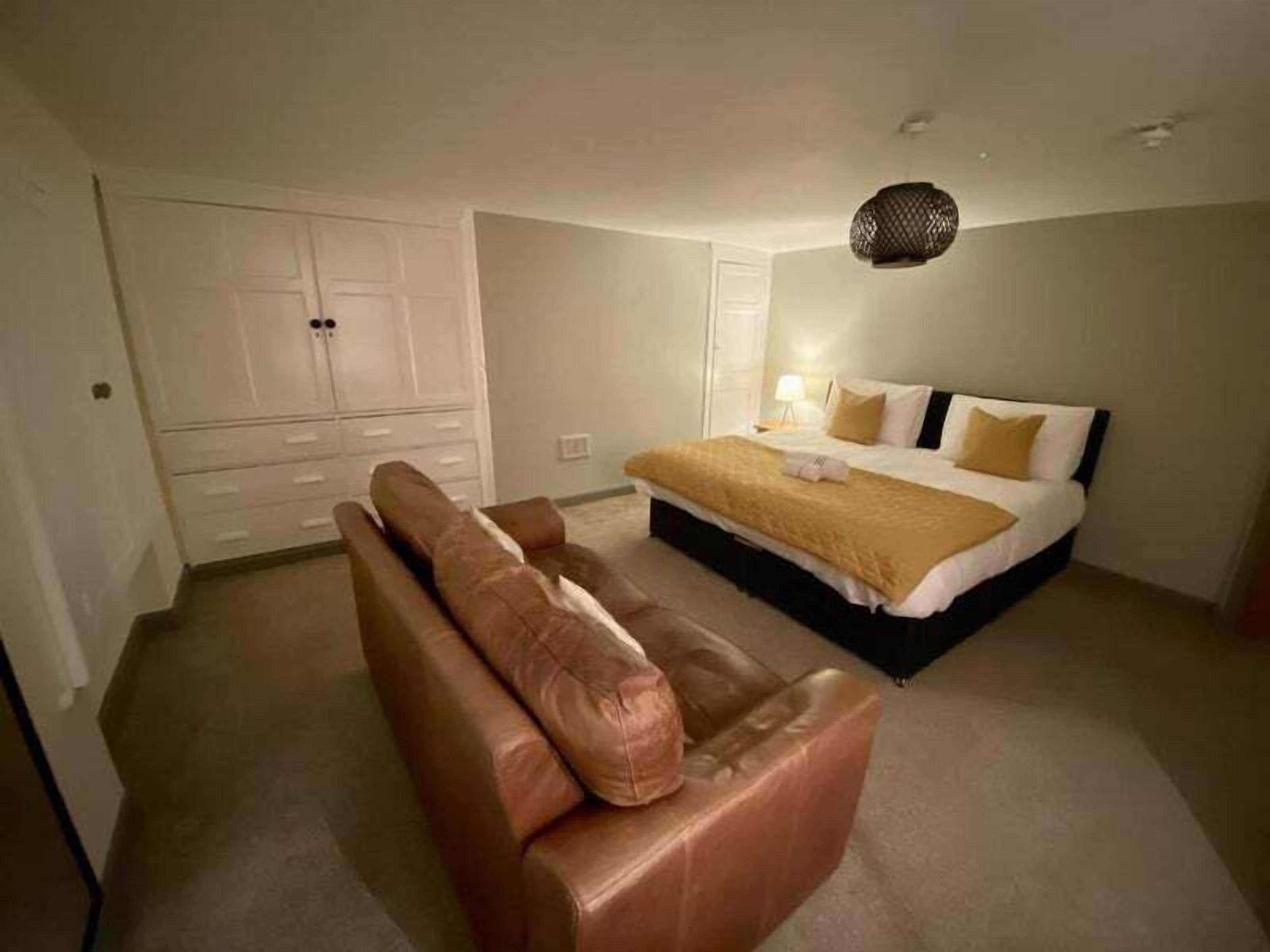 A bedroom with a bed, a sofa, and a wardrobe.